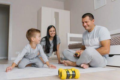 Happy family is having fun at home playing with their five-year-old son with a toy car