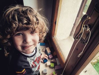 High angle portrait of cute boy playing with blocks on window sill at home