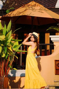 Side view of woman wearing hat standing in front of house