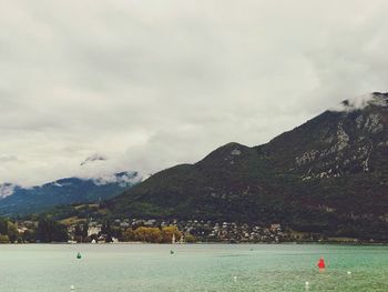 Scenic view of sea by mountains against sky