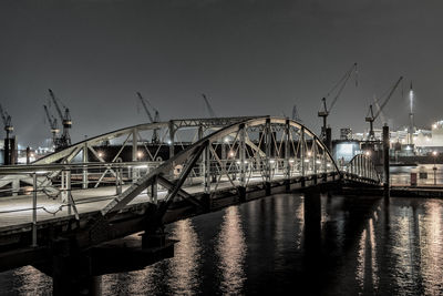 Bridge over river in city against clear sky at night