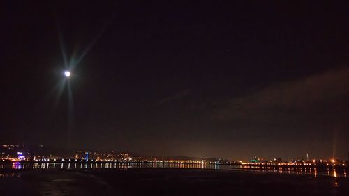 Illuminated city against sky at night