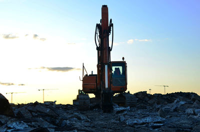 Construction site on field against sky during sunset