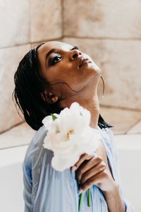 Close-up of young woman holding flower in bathtub