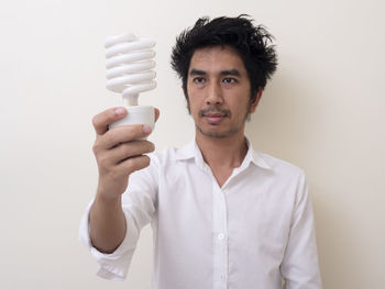 Portrait of young man standing against white background