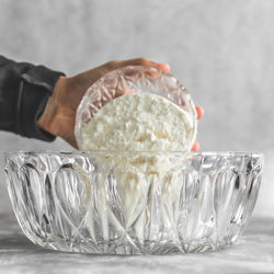 Close-up of hand holding glass bowl on table