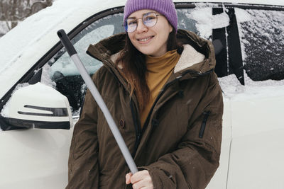 Portrait of smiling young woman standing on snow