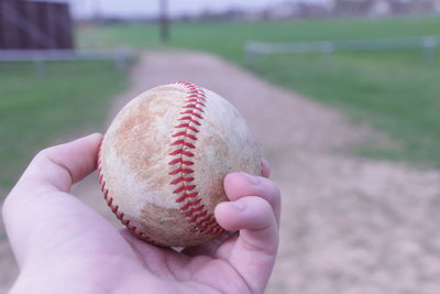 Cropped hand holding baseball on playing field