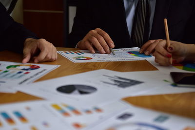 Cropped image of business colleagues discussing paperwork on table