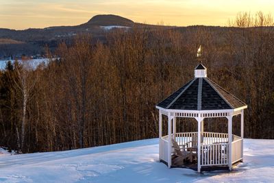 House on snowcapped mountain against sky during winter