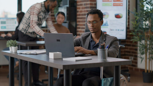 Young woman using laptop while sitting on table