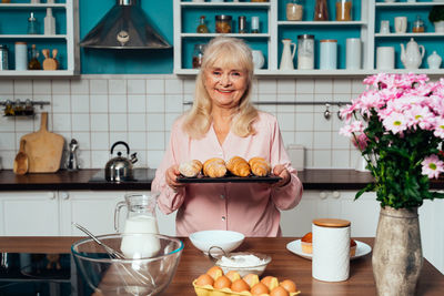 Portrait of smiling senior woman holding croissant