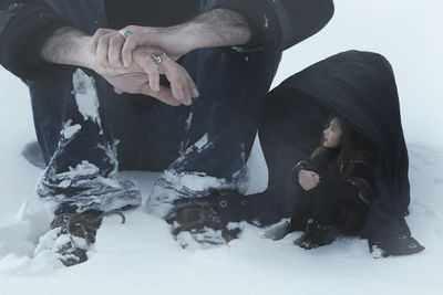 Low section of people sitting on snow