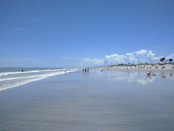 People on beach against blue sky