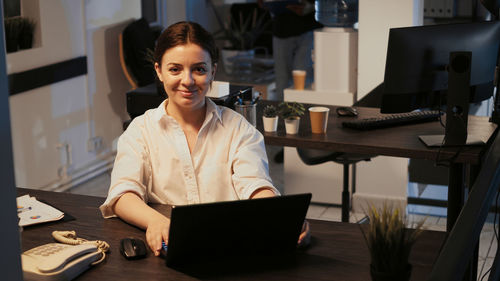 Young woman using laptop at desk in office