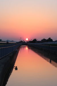 Bridge over river against sky during sunset