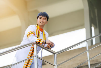 Young man standing against railing