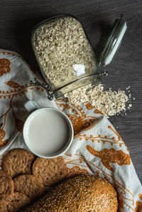 Top view of breakfast with bread, milk, cookies and oatmeal.