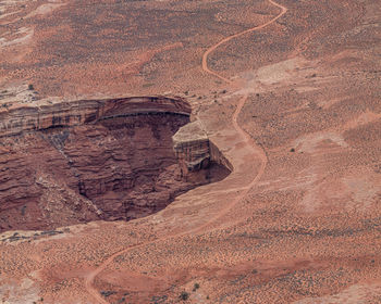 Rugged red sandstone rock formations in the eroded landscape with precarious looking road near edge