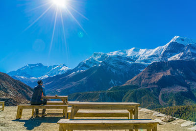 Man standing on snowcapped mountains against clear blue sky