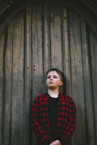 Portrait of young man standing against wall