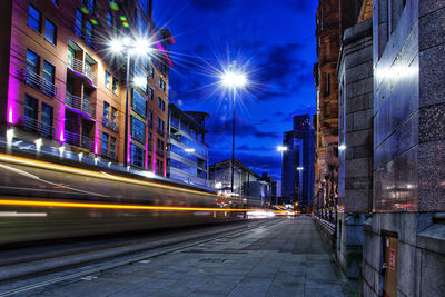 Light trails on street amidst buildings at night