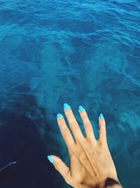 Cropped hand of woman over sea