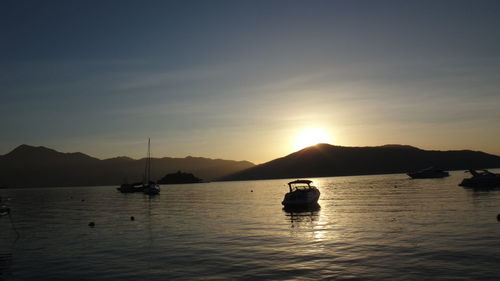 Boats moored on river against sky during sunset