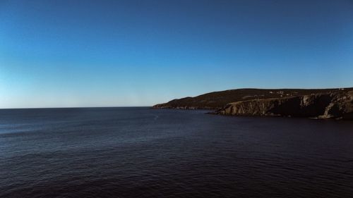 Scenic view of sea and mountains against blue sky