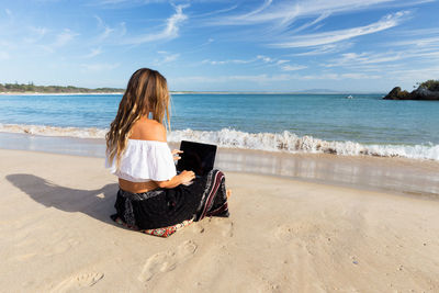 Rear view of woman sitting on beach