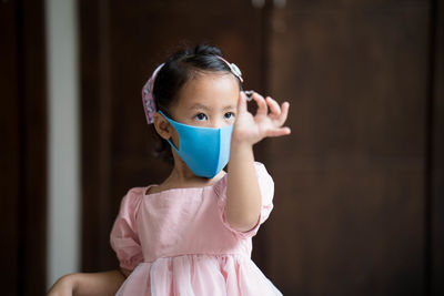 Cute little girl wearing healthy face mask to prevent virus and pm2.5 standing indoor.