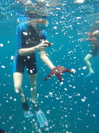 Woman photographing starfish under water