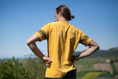 Rear view of man standing against clear blue sky