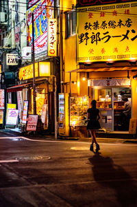 Full length of man walking on illuminated street at night