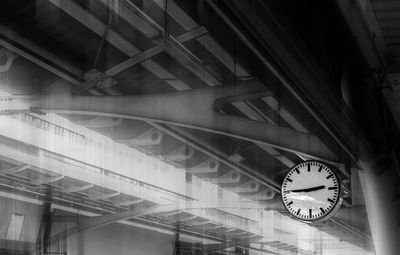 The clock shows the time on the skytrain station with iron structure roof background. 