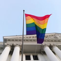 Rainbow flag hanging on historical building against clear sky