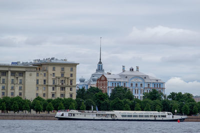 Buildings at waterfront against cloudy sky