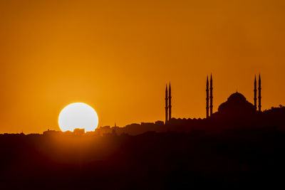 Silhouette temple against orange sky