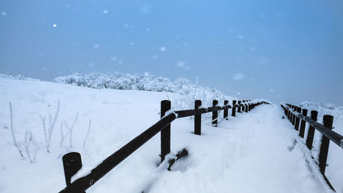Snow on railing against sky during winter