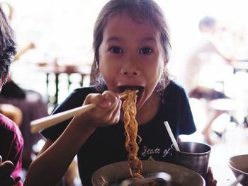 Close-up portrait of girl eating noodles at restaurant