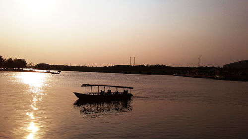 Silhouette boat in sea against clear sky during sunset