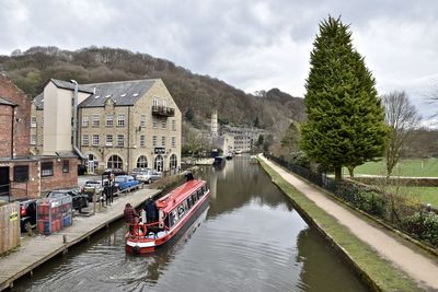 Boats in river by buildings against sky