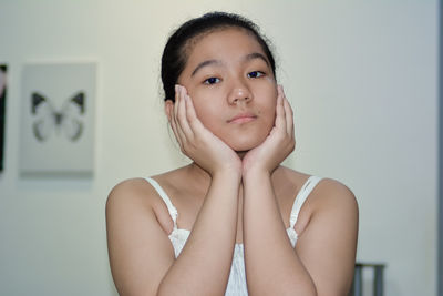 Portrait of teenage girl against wall at home