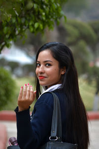 Beautiful young woman gesturing against trees