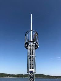 Low angle view of communications tower against clear blue sky