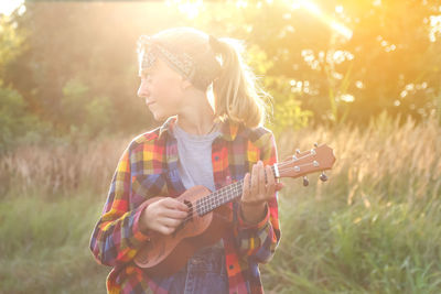 Girl with guitar on sunset. teen girl walking on nature background. little kid girl outside on green