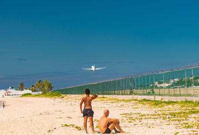 Rear view of couple on beach against sky