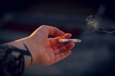 Close-up of hand holding cigarette