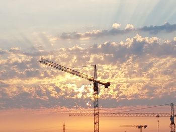 Low angle view of crane at construction site against sky during sunset