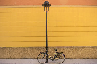 Bicycle leaning against yellow wall